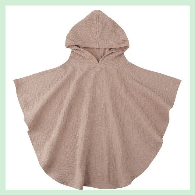 Taupe-colored children's hooded poncho made of lightweight, textured fabric. The poncho has a simple design with a rounded hem, shown against a pale green background.