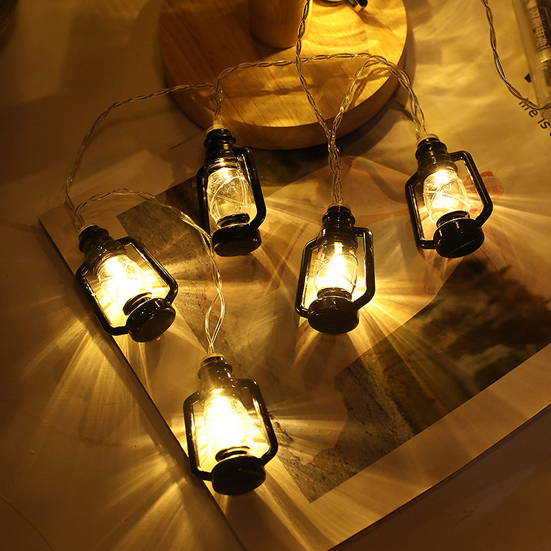 String of lantern-shaped fairy lights casting a warm, cozy glow on a wooden surface, creating patterns of light and shadow.