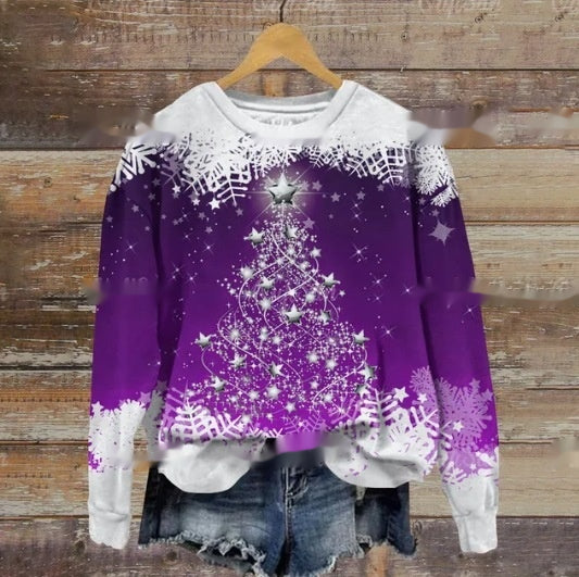 Purple and white Christmas sweater with a sparkling tree design, silver star on top, and snowflakes, paired with denim shorts, hanging on a wooden background.