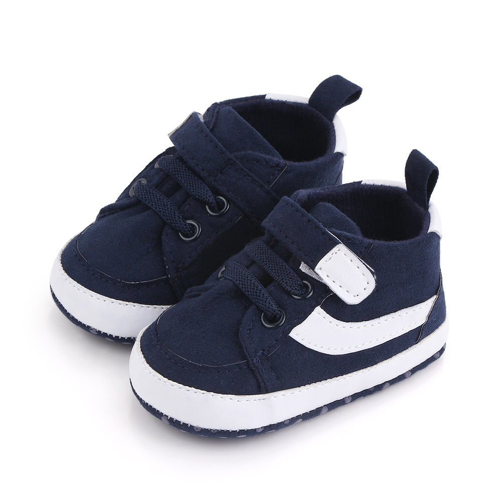 Navy blue baby sneakers with white accents, featuring laces and a velcro strap, side view on a white background.
