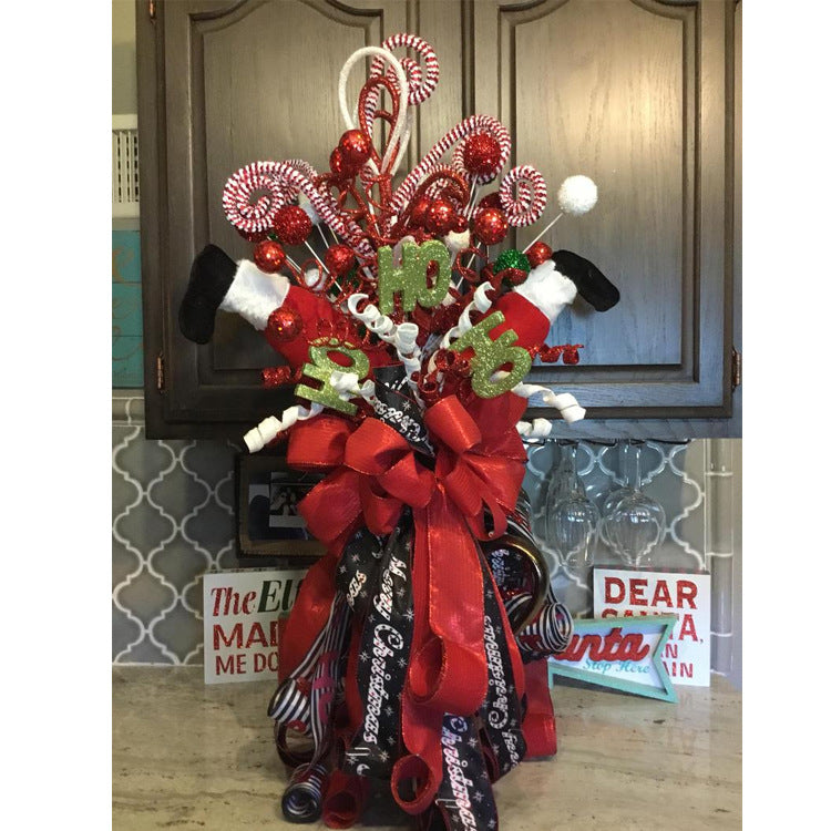 Festive decoration with red ribbons, candy canes, glittery "Ho Ho Ho", and Santa-themed items. Set against a kitchen backsplash and cabinets with holiday signs.