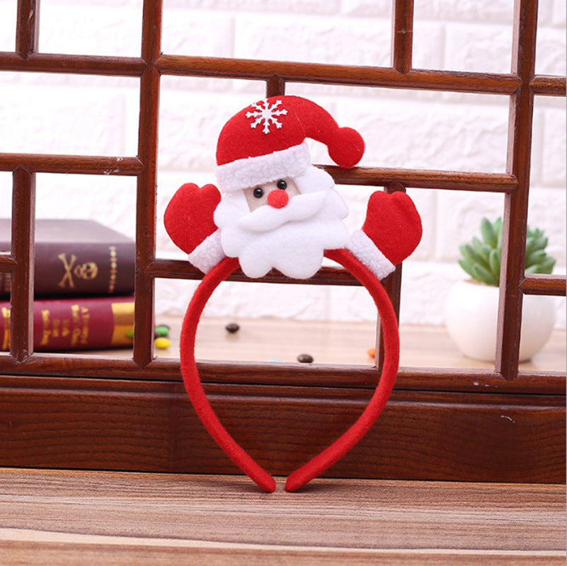 Red Santa-themed headband with white beard and snowflake detail, hung on a wooden grid. Background includes books and a potted plant.