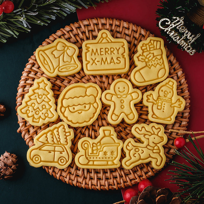 Festive Christmas cookies on a woven mat, shaped like Santa, reindeer, snowman, gingerbread man, tree, sleigh, bells, stocking, car with tree, and a "Merry X-Mas" sign.
