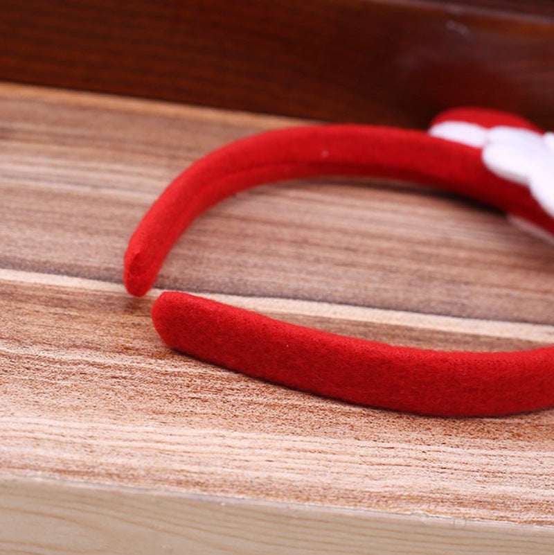 Red velvet headband resting on a wooden surface, partially visible with a hint of white detail on one side.
