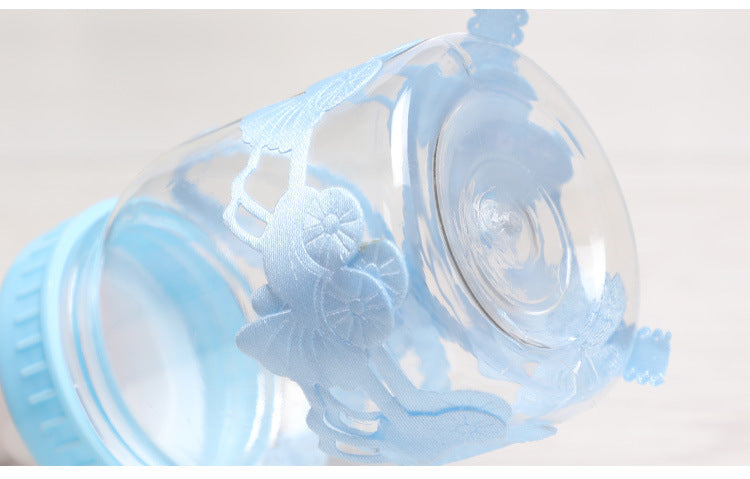 Transparent glass jar with a pastel blue lid and decorative floral pattern. The design wraps around the jar, showcasing intricate details against a blurred background.