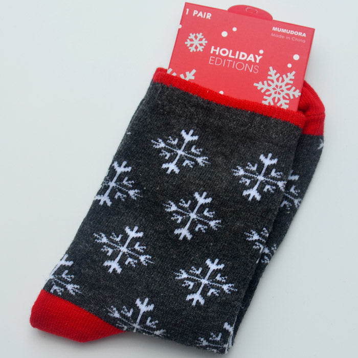 Gray socks with white snowflake patterns and red accents, packaged with a red "Holiday Editions" label featuring snowflake designs, against a white background.