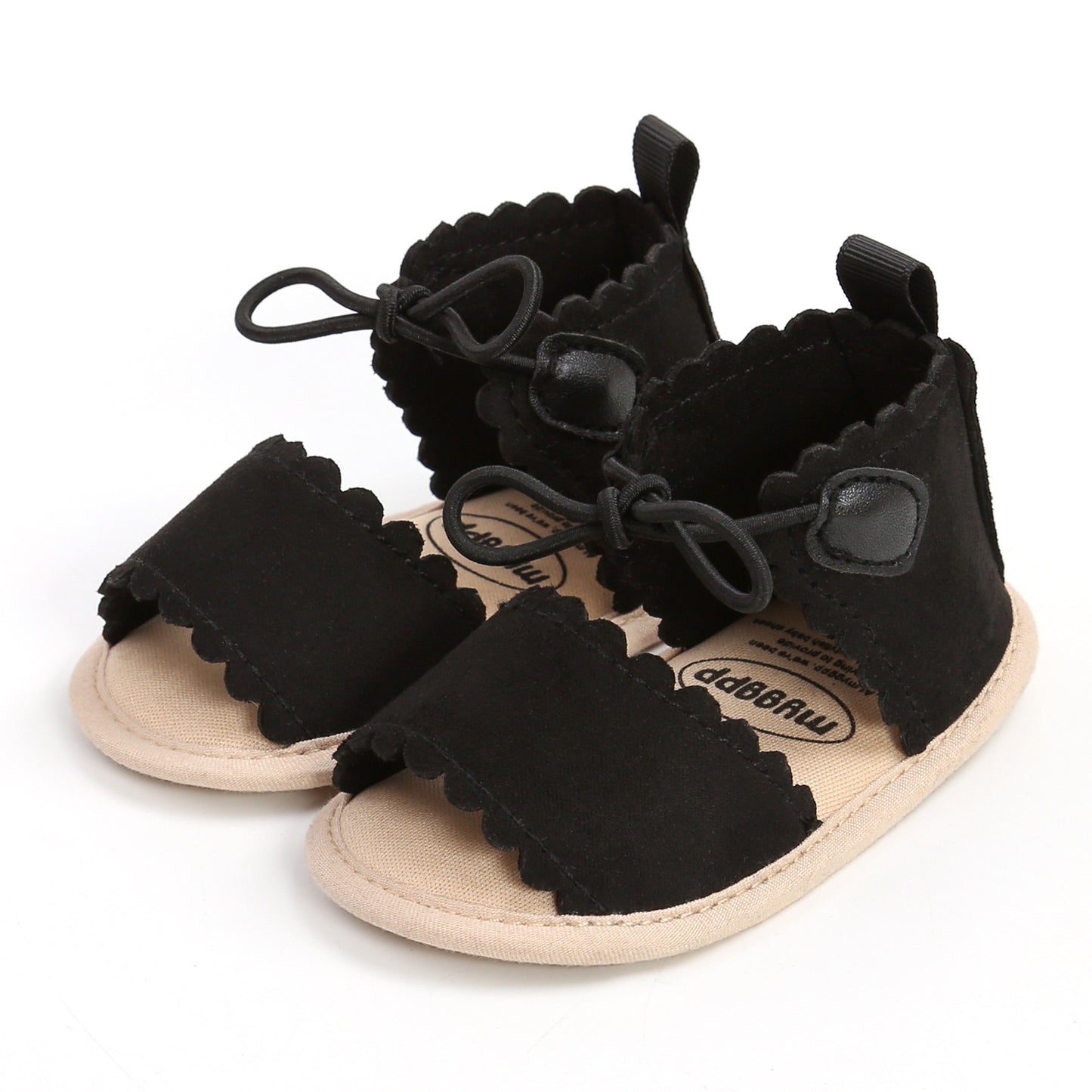 Black baby sandals with scalloped edges, front straps, adjustable laces, and beige soles.