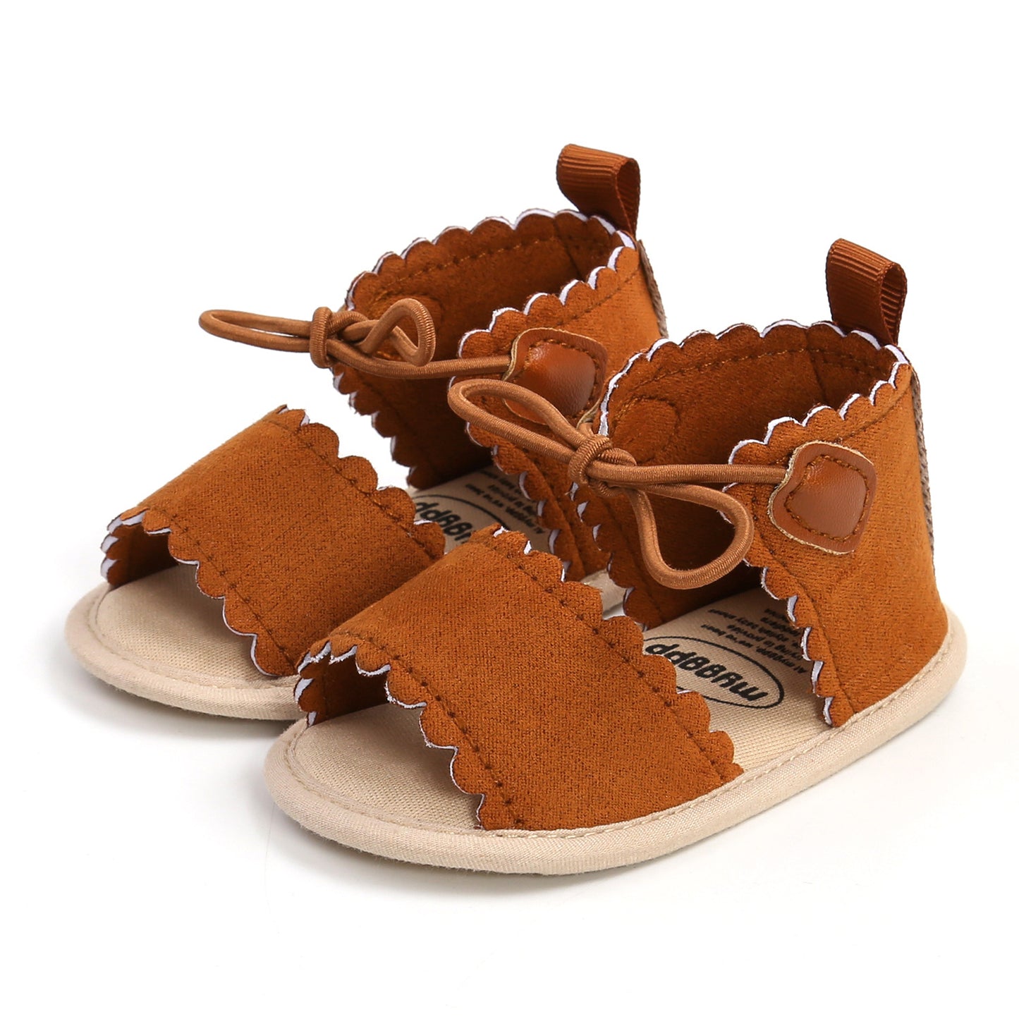 Brown baby sandals with scalloped edges, bows, and white stitching. The open-toe design features a soft sole and small pull loops at the heels.