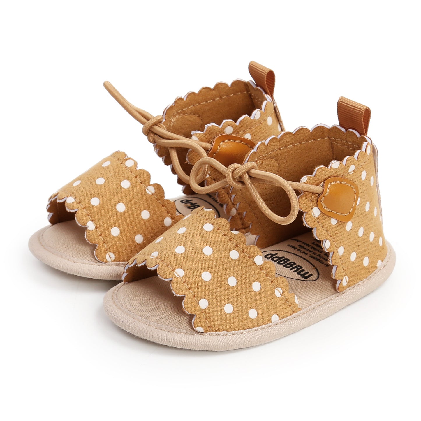 Brown baby sandals with white polka dots and scalloped edges, featuring beige soles and adjustable laces.