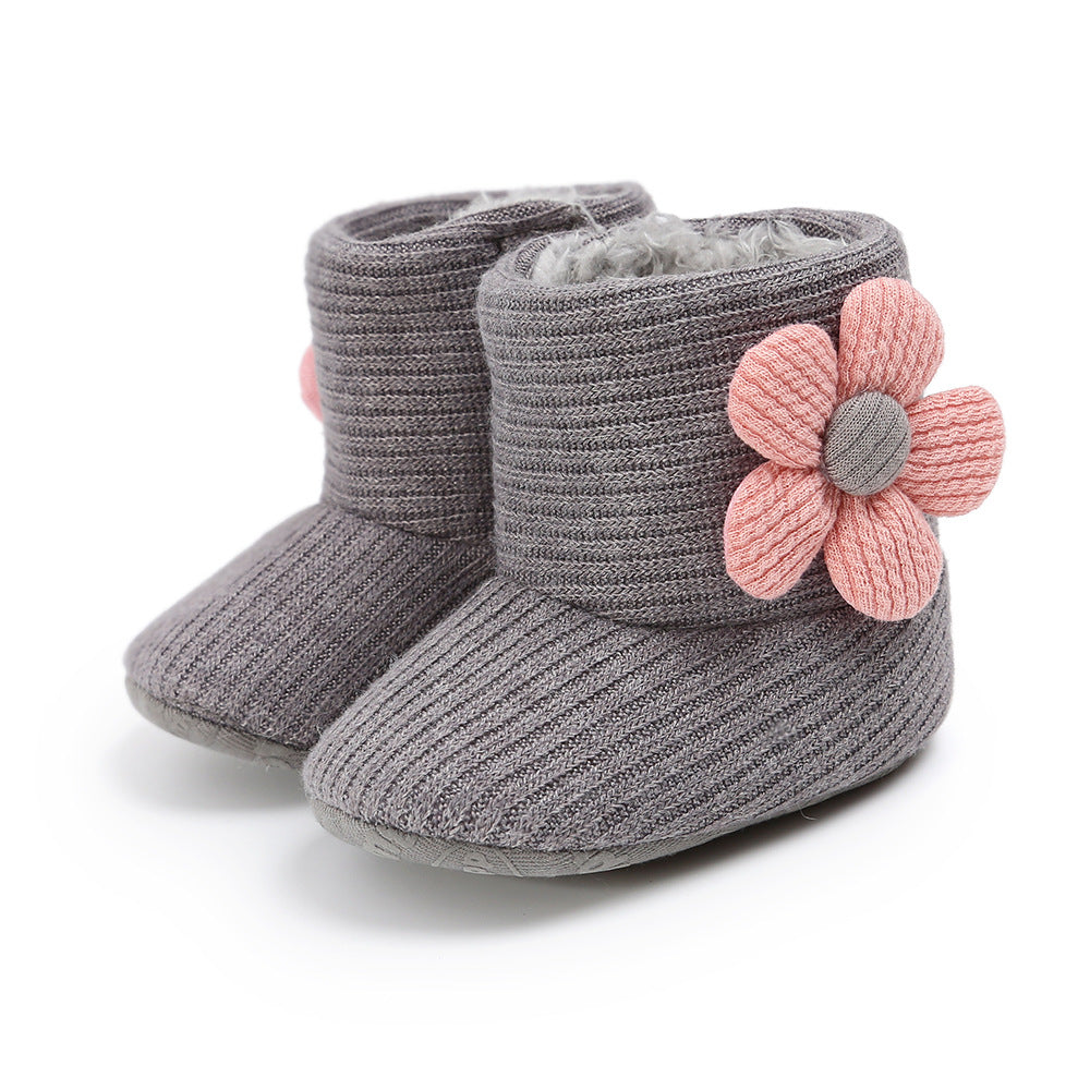Gray knitted baby boots with a soft, fuzzy interior and decorated with large pink knit flowers on the sides.