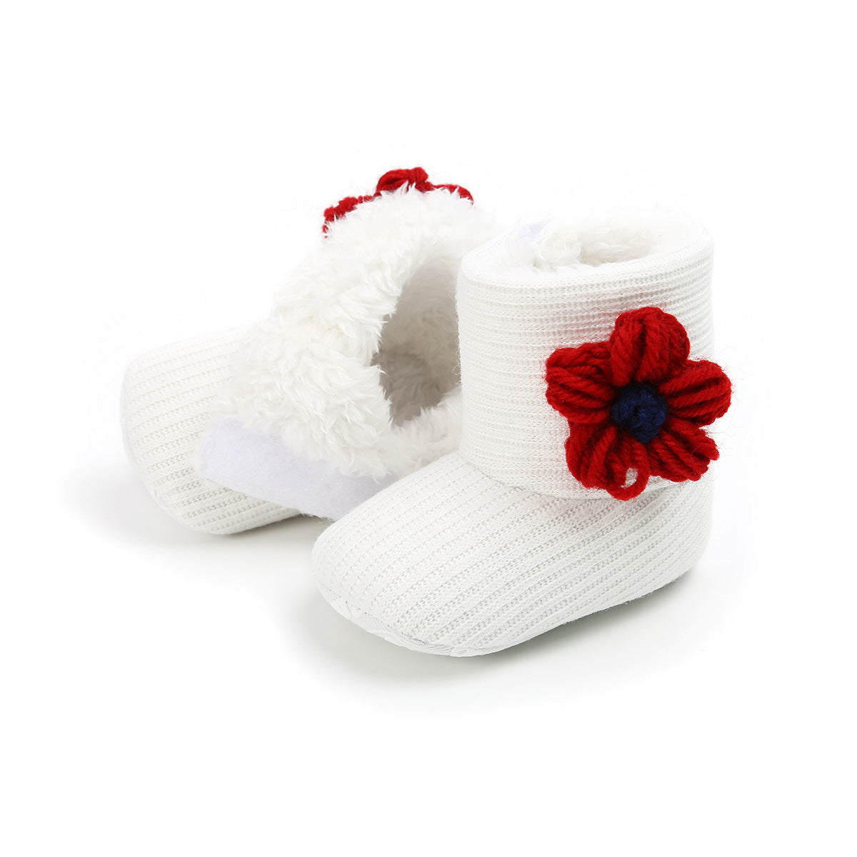 White baby booties with a textured knit pattern and fluffy lining, adorned with a red and blue yarn flower on the side, against a white background.