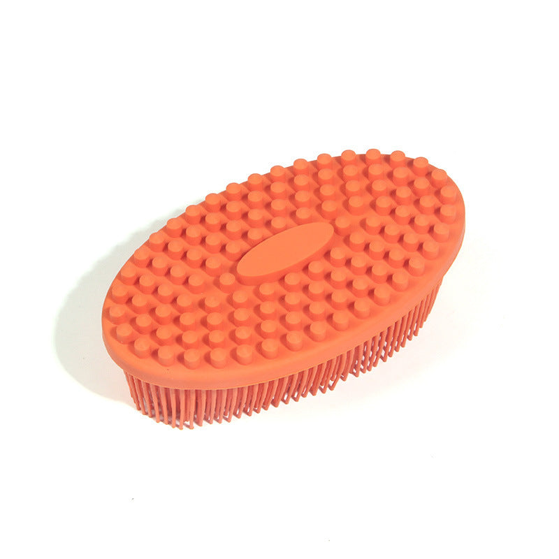 Orange silicone oval-shaped grooming brush with raised bumps on top for grip and soft bristles underneath, designed for use on animals.