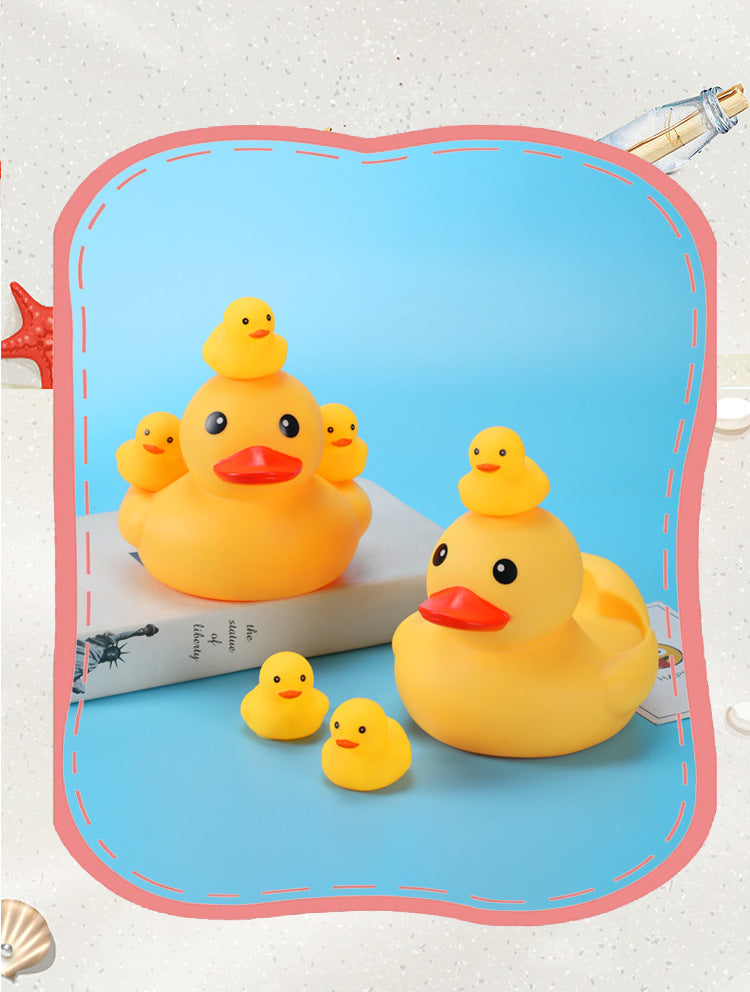 A group of yellow rubber ducks of various sizes placed on a blue surface, with a book underneath. The background features a decorative red frame and subtle ocean-themed elements.