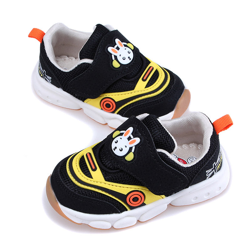 Children's black and yellow sneakers with bunny face design on Velcro straps. White soles and orange accents add a playful touch.