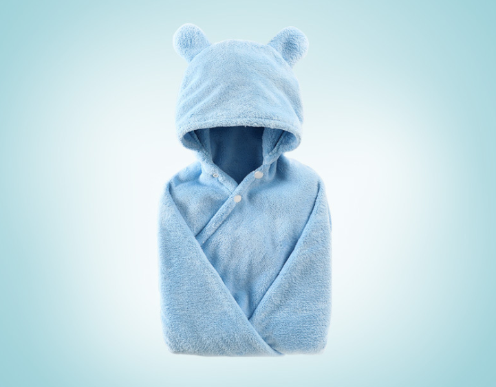 A soft blue baby blanket with a hood and bear ears, wrapped in a cozy shape with two buttons on the front. The background is a light blue gradient.