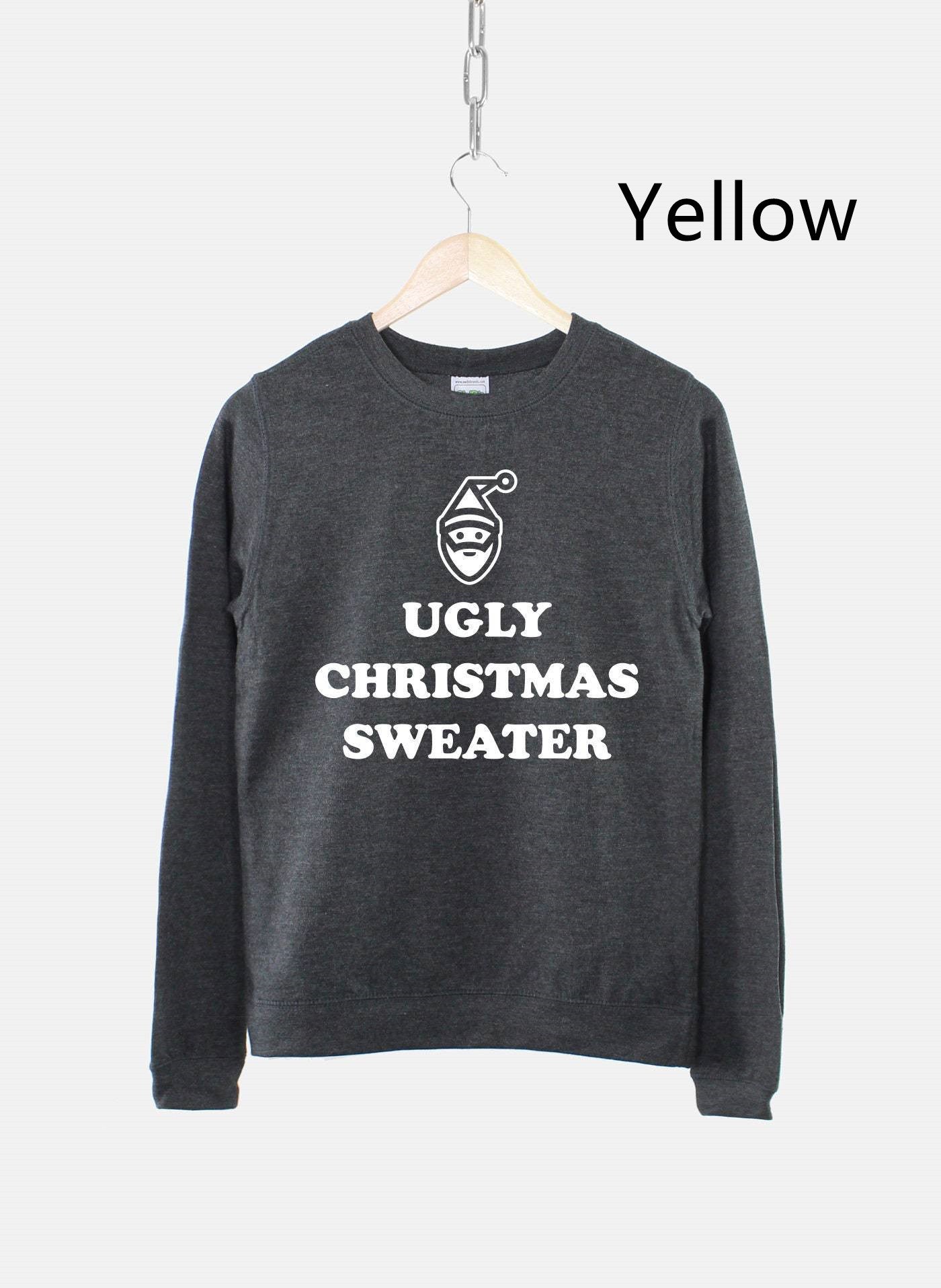 Dark gray sweater with "Ugly Christmas Sweater" text and a Santa face design, hanging by a wooden hanger against a white background with "Yellow" text at the top right.