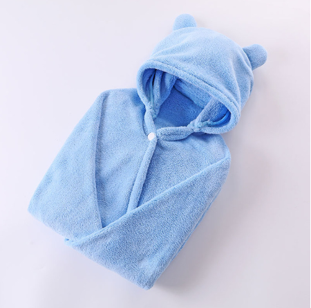 Light blue baby blanket with a hood and bear ears, folded neatly. Made of soft, plush material, it includes a snap button for easy closure, offering warmth and comfort.