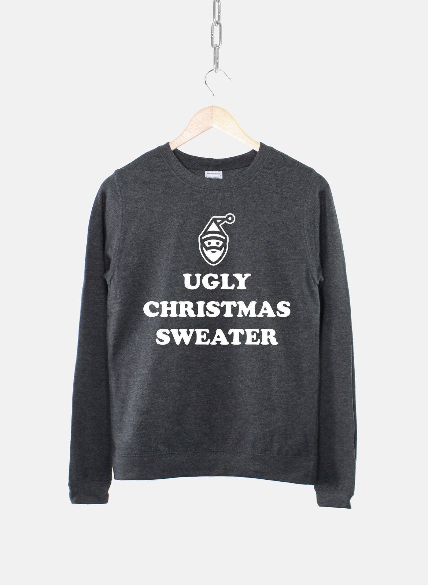 Dark gray sweater on hanger with "Ugly Christmas Sweater" text and a simple Santa face design. Hangs against a light gray background.