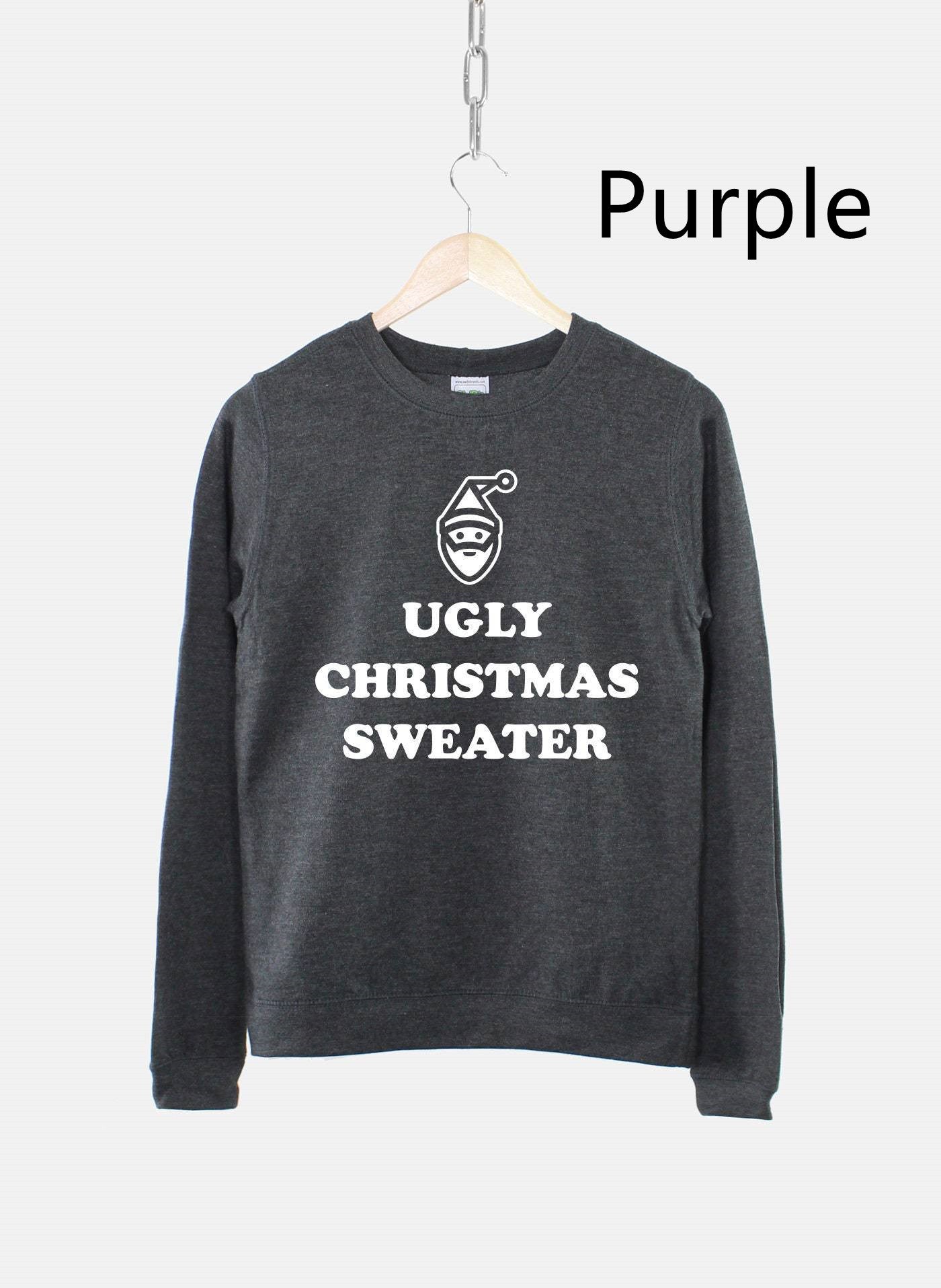 Dark gray sweater with "Ugly Christmas Sweater" and a Santa face printed in white. It hangs on a wooden hanger against a light gray background labeled "Purple."