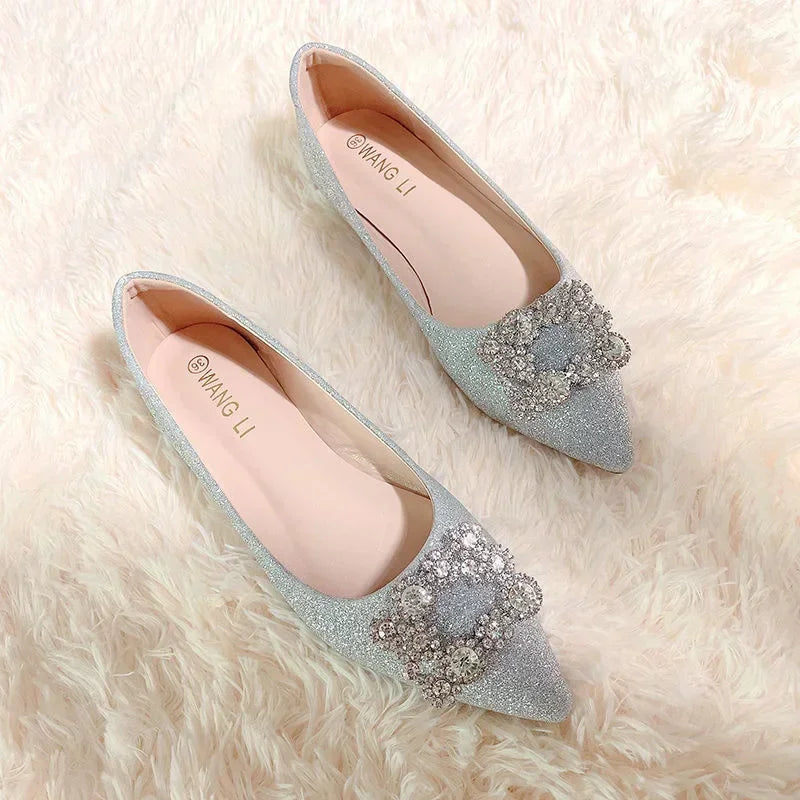 Sparkly gray pointed-toe flats with decorative silver crystal bows on a soft cream shag carpet.