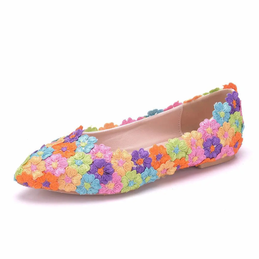 Colorful flat shoe covered in embroidered flowers in shades of blue, pink, orange, green, and purple; features a pointed toe and neutral inner lining.