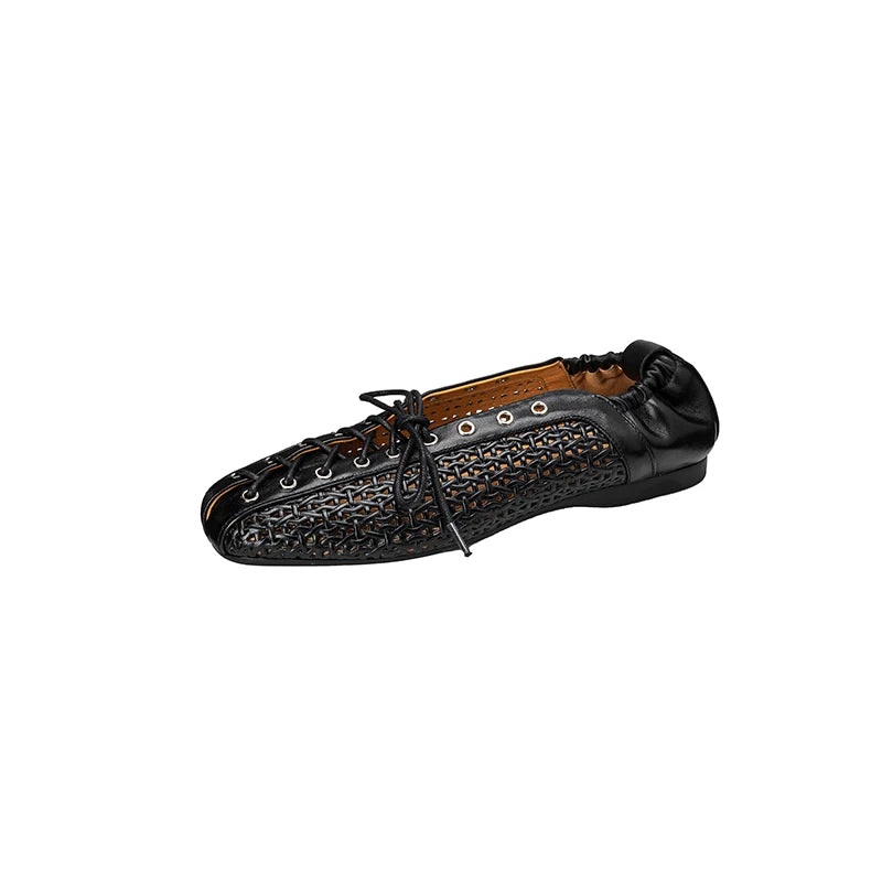 Black leather shoe with intricate woven detailing, eyelets, black laces, and a soft heel. The interior is tan. The design blends elegance with a modern twist.