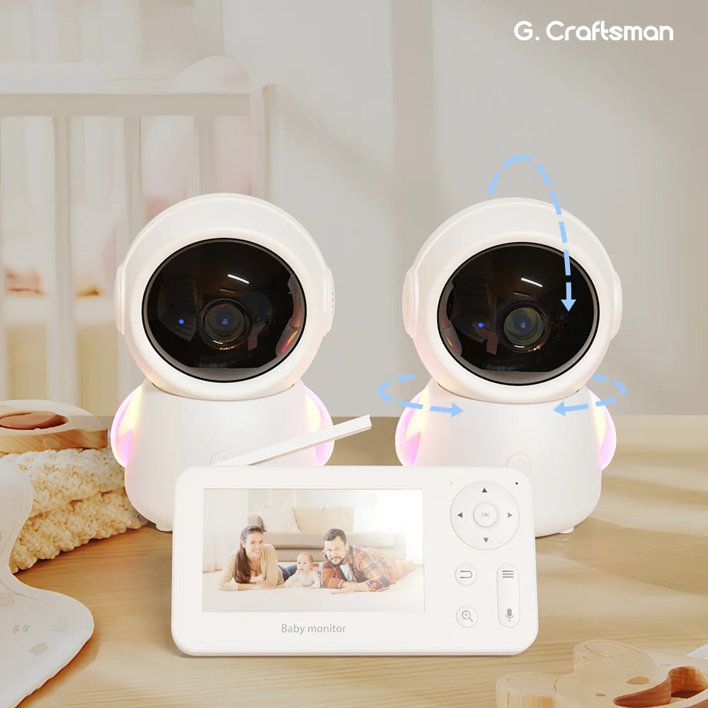 Two spherical baby monitor cameras with glowing bases and rotation arrows are on a table. A monitor displays a family picture, indicating its use for monitoring.