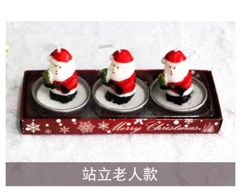 Three Santa Claus-shaped candles in a red tray, adorned with snowflakes and "Merry Christmas" text.