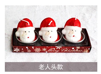 Three Santa-themed candles in a tray with "Merry Christmas" written on it. Each candle features a Santa head with a red hat and is placed in a metal holder.