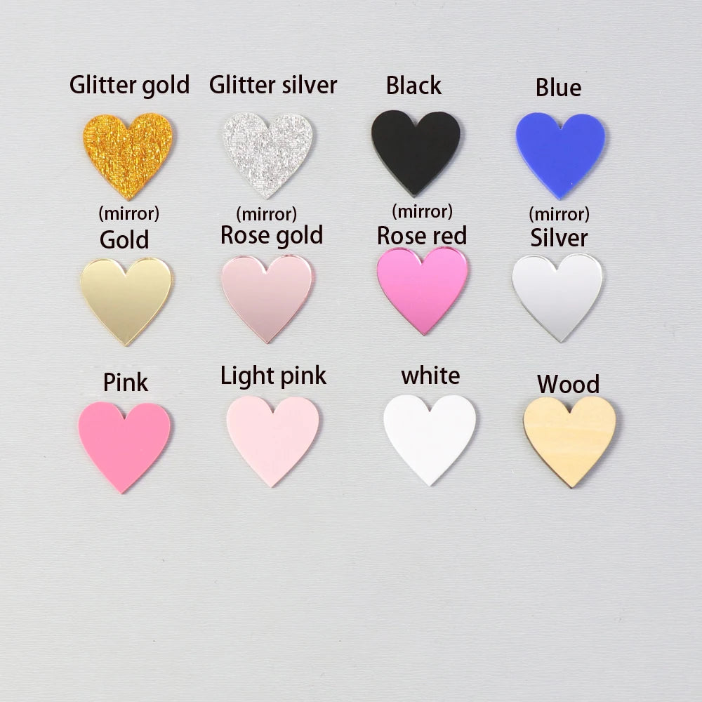 Twelve heart-shaped buttons displayed in rows, featuring various colors and finishes: glitter gold, glitter silver, black, blue, gold, rose gold, rose red, silver, pink, light pink, white, and wood.