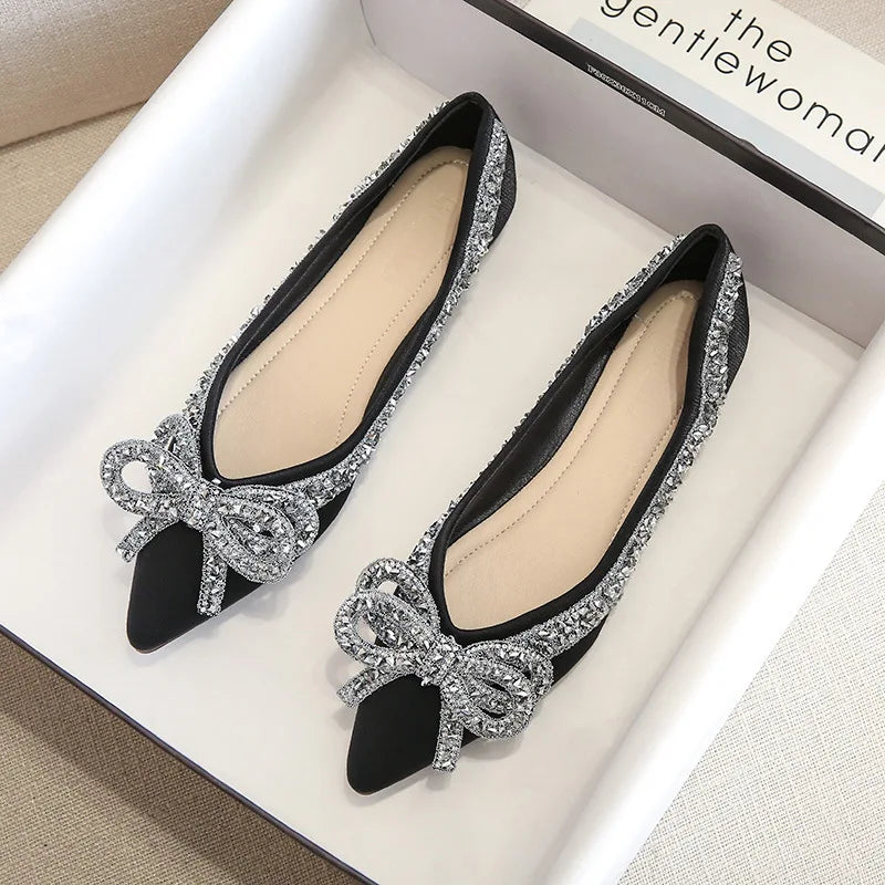 Elegant black flats adorned with sparkling silver sequins and bow details, displayed in a white box with a magazine labeled "the gentlewoman" partially visible.