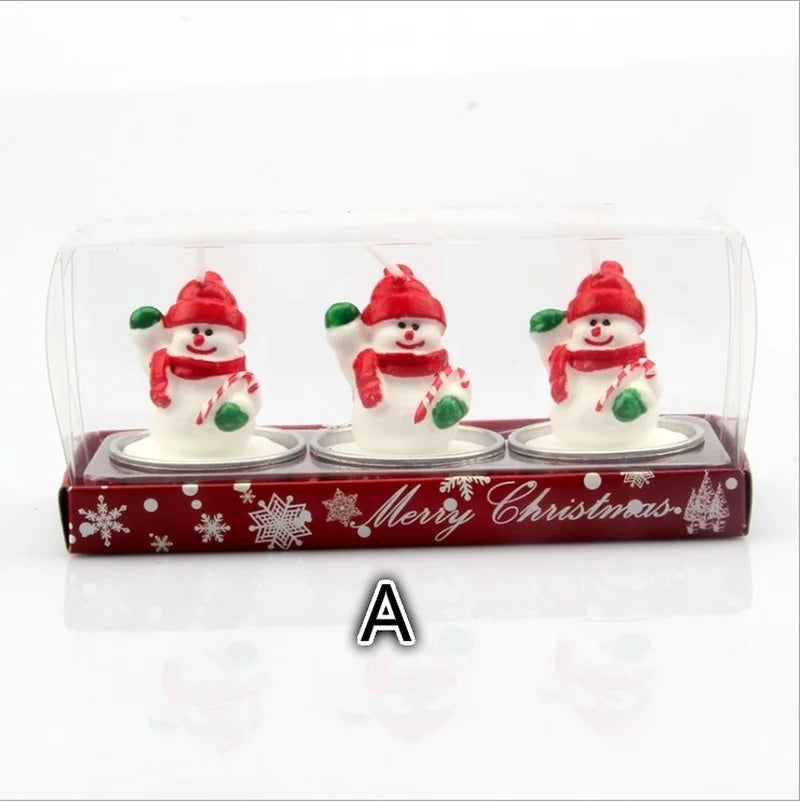 Three snowman-shaped candles wearing red hats and scarves with green mittens, packaged in a red box labeled "Merry Christmas" adorned with snowflakes.