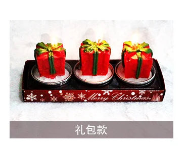 Three red and green Christmas present-shaped candles on a tray with "Merry Christmas" text. Snowflake designs decorate the tray.