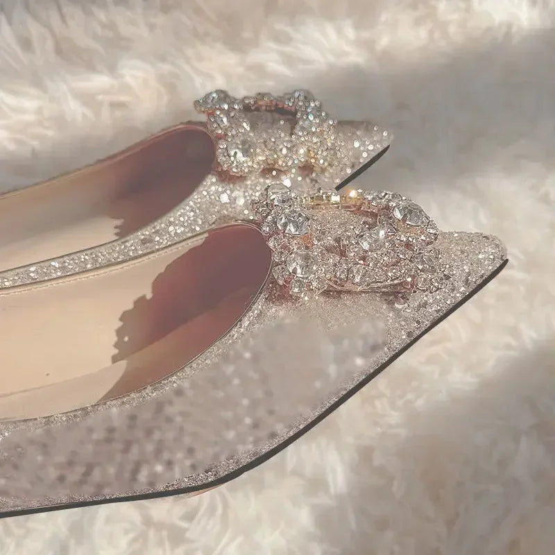 Close-up of elegant, sparkly designer flats adorned with intricate crystal embellishments, resting on a soft, textured white surface, capturing light and shadows.
